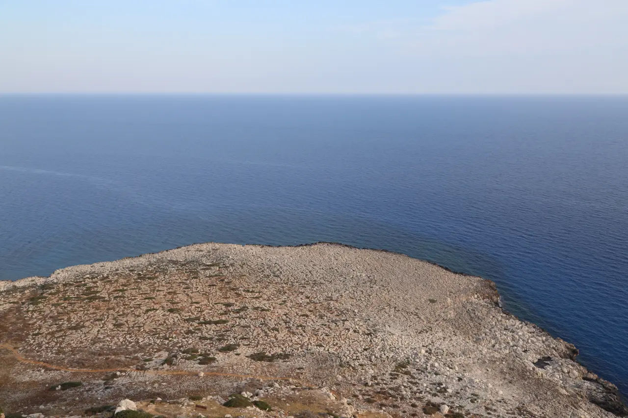 View from a hilltop over a bare, stony headland into the open sea