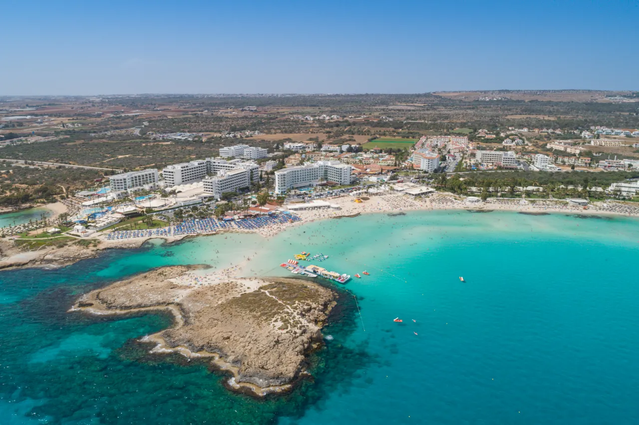 Aerial view of the small island in the turquoise bay, with the beach and hotels behind